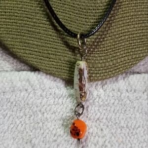 White orange glass pendant on black cord necklace